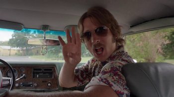 Movie still from “Everybody Wants Some!!” (2016), directed by Richard Linklater – A man in sunglasses and a floral shirt is sitting in the driver's seat of a car; Close Up shot, Over the shoulder angle