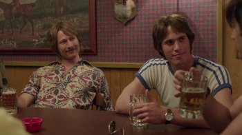 Movie still from “Everybody Wants Some!!” (2016), directed by Richard Linklater – Two men sitting at a table with a drink; Medium shot, Over the shoulder angle