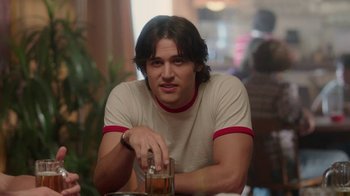 Movie still from “Everybody Wants Some!!” (2016), directed by Richard Linklater – A man sitting at a table with a drink in front of him; Medium shot, Over the shoulder angle