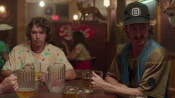 Movie still from “Everybody Wants Some!!” (2016), directed by Richard Linklater – Two men sitting at a table with drinks in front of them; Medium shot, Over the shoulder angle