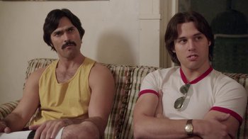 Movie still from “Everybody Wants Some!!” (2016), directed by Richard Linklater – Two men sitting on a couch in front of a wall; Close Up shot, Over the shoulder angle
