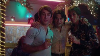 Movie still from “Everybody Wants Some!!” (2016), directed by Richard Linklater – A group of young men standing next to each other holding drinks; Medium shot, Low angle