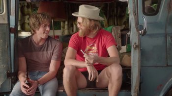 Movie still from “Everybody Wants Some!!” (2016), directed by Richard Linklater – A man sitting on a truck with another man sitting next to him; Medium shot, Over the shoulder angle