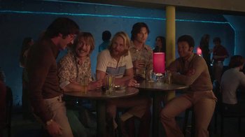 Movie still from “Everybody Wants Some!!” (2016), directed by Richard Linklater – A group of people sitting at a table in a room; Medium shot, Over the shoulder angle
