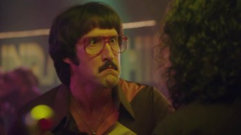 Movie still from “Everybody Wants Some!!” (2016), directed by Richard Linklater – A man with a beard and mustache wearing glasses and a wig; Close Up shot, Over the shoulder angle