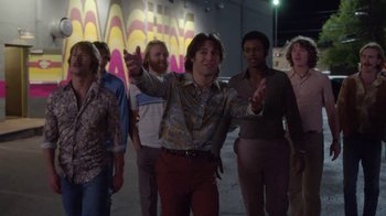 Movie still from “Everybody Wants Some!!” (2016), directed by Richard Linklater – A group of people walking down a street; Wide shot, Low angle