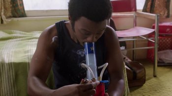 Movie still from “Everybody Wants Some!!” (2016), directed by Richard Linklater – A man is smoking a hookah pipe in a living room; Medium shot, High angle