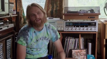 Movie still from “Everybody Wants Some!!” (2016), directed by Richard Linklater – A man sitting in front of a bunch of records; Medium shot, Over the shoulder angle