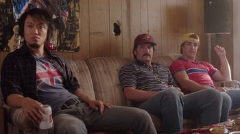 Movie still from “Everybody Wants Some!!” (2016), directed by Richard Linklater – A group of men sitting on a couch; Medium shot, Low angle