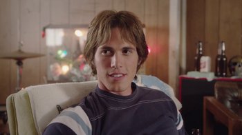 Movie still from “Everybody Wants Some!!” (2016), directed by Richard Linklater – A young man sitting on a couch in front of a christmas tree; Close Up shot, Over the shoulder angle