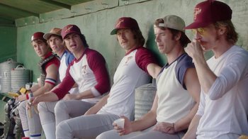 Movie still from “Everybody Wants Some!!” (2016), directed by Richard Linklater – A group of baseball players sitting in a dugout; Medium shot, High angle