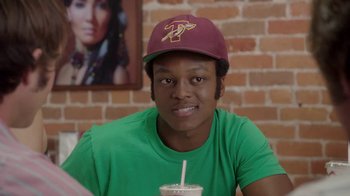 Movie still from “Everybody Wants Some!!” (2016), directed by Richard Linklater – A young man wearing a hat is holding a drink; Close Up shot, Over the shoulder angle