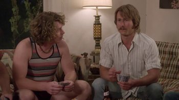 Movie still from “Everybody Wants Some!!” (2016), directed by Richard Linklater – Two people sitting on a couch talking to each other; Medium shot, Over the shoulder angle