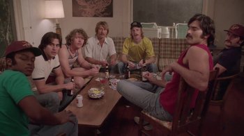 Movie still from “Everybody Wants Some!!” (2016), directed by Richard Linklater – A group of people sitting around a table; Medium shot, Low angle