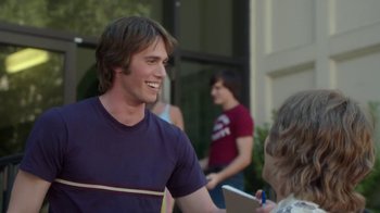 Movie still from “Everybody Wants Some!!” (2016), directed by Richard Linklater – A young man smiles while talking to a woman; Medium shot, Over the shoulder angle