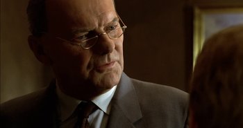 Movie still from “Evil” (2003), directed by Mikael Håfström – An older man wearing glasses and a suit; Close Up shot, Low angle