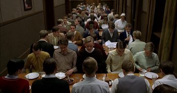 Movie still from “Evil” (2003), directed by Mikael Håfström – A large group of people sitting at a table eating food; Wide shot, High angle