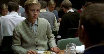 Movie still from “Evil” (2003), directed by Mikael Håfström – A man sitting at a table with a plate of food in front of him; Medium shot, Over the shoulder angle
