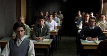 Movie still from “Evil” (2003), directed by Mikael Håfström – A group of people sitting at desks in a classroom; Medium shot, High angle