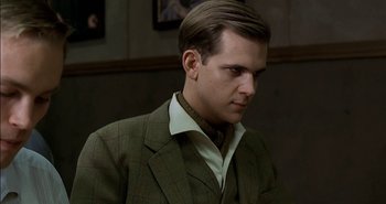 Movie still from “Evil” (2003), directed by Mikael Håfström – A man wearing a suit and tie in front of a wall; Close Up shot, Over the shoulder angle