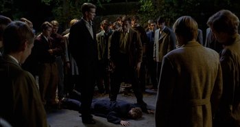 Movie still from “Evil” (2003), directed by Mikael Håfström – A group of men standing around a man laying on the ground; Wide shot, High angle