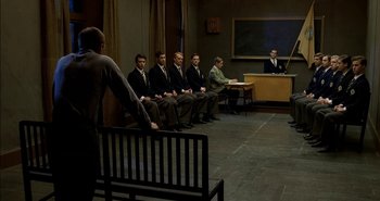 Movie still from “Evil” (2003), directed by Mikael Håfström – A group of men sitting in front of a man in a courtroom; Wide shot, High angle