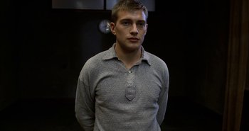 Movie still from “Evil” (2003), directed by Mikael Håfström – A man in a gray shirt is looking at the camera; Close Up shot, Low angle