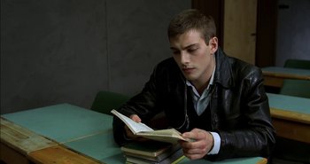 Movie still from “Evil” (2003), directed by Mikael Håfström – A man sitting at a table reading a book; Medium shot, High angle