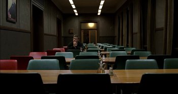 Movie still from “Evil” (2003), directed by Mikael Håfström – A man sitting at a table in front of many empty chairs; Wide shot, High angle