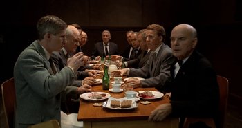 Movie still from “Evil” (2003), directed by Mikael Håfström – A group of men sitting around a table eating; Wide shot, High angle