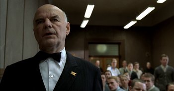 Movie still from “Evil” (2003), directed by Mikael Håfström – An older man in a suit and bow tie; Close Up shot, Low angle
