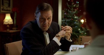 Movie still from “Evil” (2003), directed by Mikael Håfström – A man sitting at a table with a watch; Close Up shot, Low angle