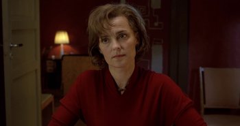 Movie still from “Evil” (2003), directed by Mikael Håfström – A woman in a red shirt sitting in front of a lamp; Close Up shot, Over the shoulder angle