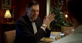 Movie still from “Evil” (2003), directed by Mikael Håfström – An older man sitting at a dinner table with his hands raised; Close Up shot, Low angle