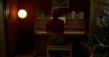 Movie still from “Evil” (2003), directed by Mikael Håfström – A woman sitting on a chair playing a piano; Wide shot, High angle