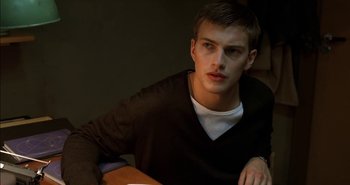 Movie still from “Evil” (2003), directed by Mikael Håfström – A young man sitting in a chair in a dark room; Close Up shot, Low angle