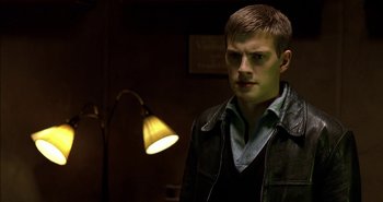 Movie still from “Evil” (2003), directed by Mikael Håfström – A man standing in front of a lamp in a dark room; Close Up shot, Low angle