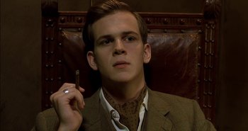 Movie still from “Evil” (2003), directed by Mikael Håfström – A man in a suit and tie smoking a cigarette; Close Up shot, Low angle