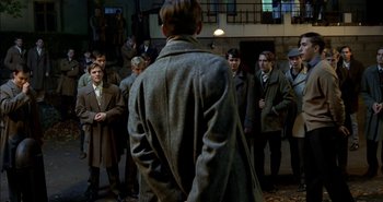 Movie still from “Evil” (2003), directed by Mikael Håfström – A group of men standing around a building; Wide shot, Over the shoulder angle