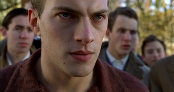 Movie still from “Evil” (2003), directed by Mikael Håfström – A young man's face with another young man in the background; Close Up shot, Low angle