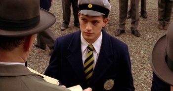 Movie still from “Evil” (2003), directed by Mikael Håfström – A man in a suit and tie holding a book; Close Up shot, High angle