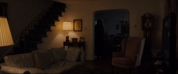 Movie still from “Glass” (2019), directed by M. Night Shyamalan – A living room filled with furniture next to a staircase; Wide shot, Over the shoulder angle