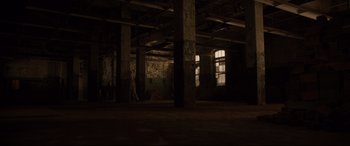 Movie still from “Glass” (2019), directed by M. Night Shyamalan – A person walking in an empty room with pillars; Extreme Wide shot, Low angle