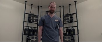 Movie still from “Glass” (2019), directed by M. Night Shyamalan – A man with a beard wearing a gray shirt; Medium shot, Low angle