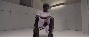 Movie still from “Glass” (2019), directed by M. Night Shyamalan – A man sitting in a wheel chair in a room; Medium shot, High angle