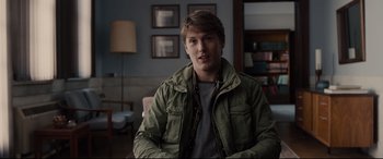 Movie still from “Glass” (2019), directed by M. Night Shyamalan – A young man sitting on a couch in a living room; Medium shot, Over the shoulder angle