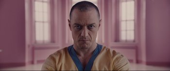 Movie still from “Glass” (2019), directed by M. Night Shyamalan – A person wearing a yellow and blue shirt; Close Up shot, Low angle