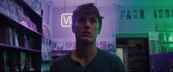 Movie still from “Glass” (2019), directed by M. Night Shyamalan – A young man is standing in front of a neon sign; Close Up shot, Low angle