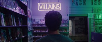 Movie still from “Glass” (2019), directed by M. Night Shyamalan – A man standing in front of a store with a neon sign above his head; Medium shot, Low angle