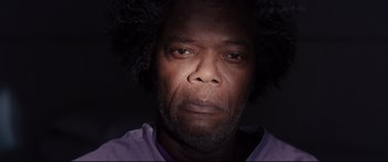 Movie still from “Glass” (2019), directed by M. Night Shyamalan – A person wearing a purple shirt; Close Up shot, Low angle